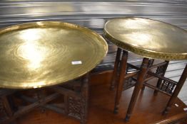 An eastern brass topped table with folding wooden carved base