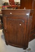 A 19th Century oak corner cupboard having shaped shelf interior
