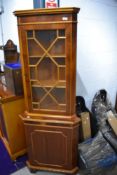 A modern yew wood corner cupboard having glazed display