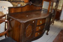 An early 20th Century mahogany sideboard having ledge back and gadrooned edge, with serpentine