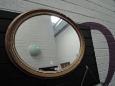 An oval framed gilt and gesso mantle mirror