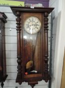 A British enamelled faced wall clock having weighted pendulum in mahogany case