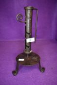 A wrought iron candle stick on tripod base