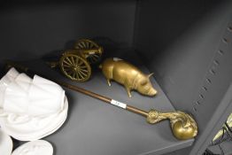 A brass figure of a pig and a brass model cannon also an eagle claw fire poker
