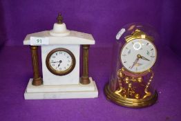 A glass domed anniversary clock by Kundo and a similar marble mantle clock