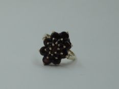 An oval garnet triple cluster dress ring having a raised basket mount on a 9ct gold loop, size O &