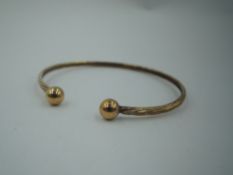 A 9ct gold tension bangle having ball knops, approx 3.4g