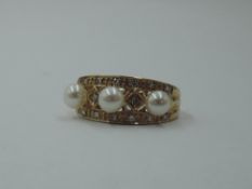 A 9ct gold band ring having three small cultured pearls within a diamond chip set border, size M &