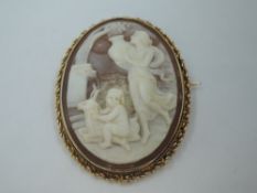 A conch shell cameo brooch depicting a mythical garden scene of a maiden carrying an urn beside a