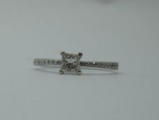 A princess cut diamond solitaire, approx 0.30ct in a four claw mount to diamond chip set shoulders