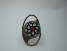 A silver ring by Caithness glass having a millefiori glass panel in a stylised oval mount, size