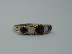 A five stone garnet and opal dress ring having a moulded scroll gallery mount on a 9ct gold loop,