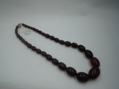 A long string of graduated cherry amber oval beads on a later gold plated clasp, approx 24'