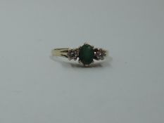 An emerald and diamond dress ring having a central oval emerald flanked by two diamonds to