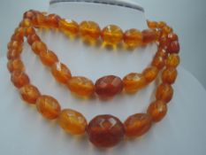 A triple string of graduated oval facetted amber beads having a rolled gold box clasp, approx 13.