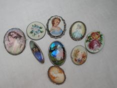 Eight brooches of various forms including cameo, ceramic, butterfly wing and enamelled all having