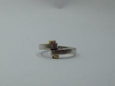 A gent's white metal ring having yellow metal screw head decoration to cross over detail, no marks