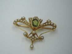 An Edwardian yellow metal brooch having a central peridot with seed pearl decoration, (1 pearl
