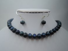 A string of knotted iridescent blue baroque pearls and matching drop earrings having silver