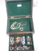 A vintage treen box containing a selection of brooches and diamante