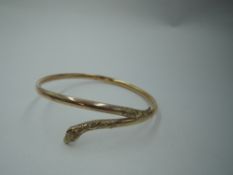 A 9ct gold snake bangle having paste eyes and moulded decoration to head and tail, approx 5.4g