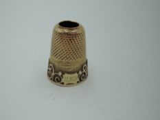A yellow metal thimble having applique decoration to side and monogram, approx 4.5g (AF)