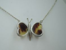 A silver butterfly pendant having tortoise shell panel wings on a fixed silver chain