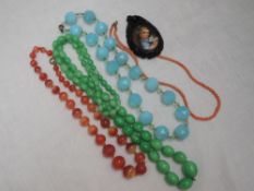 Four strings of beads including painted glass, orange striped agate, coral, and turquoise facetted