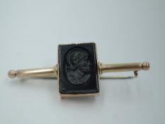 A rose metal bar brooch having a central onyx intaglio depicting a Roman Centurion in a collared