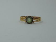 A 22ct gold composite ring having an added peridot stone in rose metal collared mount, size U and