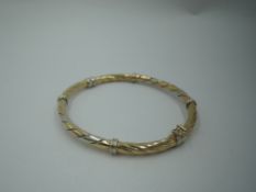A 9ct triple coloured gold hinged bangle having twist decoration, approx 9.7g