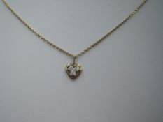 A yellow metal heart pendant having a trio of small diamonds in an open mount on a yellow metal