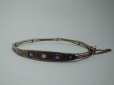 A Victorian 9ct rose gold hinged bangle having sapphire and diamond set lozenge shaped panel and