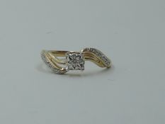 A small diamond solitaire dress ring in an illusionery square setting with diamond chip set swirl