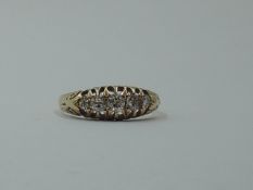A graduated five stone diamond dress ring in a claw set gallery mount to engraved shoulders on an