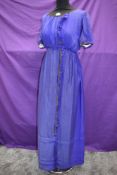 An early 20th century blue silk or silk blend dress having metallic thread edging and glass bead