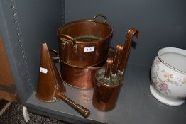 A selection of copper kitchen wares including graduated scoops two fish steamers and funnel scoop