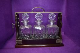A modern three bottle tantalus by PB & S having crystal cut decanters