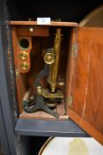 An early 20th century scientific microscope having a brass and cast body with mahogany case made