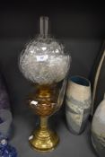 A brass bodied oil burning lamp having yellow glass well with shaped shade