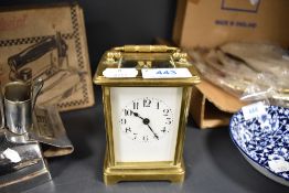 A vintage brass carriage clock having visible escape and enamel face and bevelled glass sides,