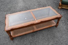 A modern glass top coffee table in the classical style having canework undertier, approx 132 x 57cm