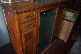 A Victorian oak (formerly gun) cabinet, central display flanked by drawers over narrow cupboard,