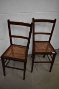 A pair of Edwardian mahogany bedroom chairs having canework seats