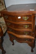 A reproduction walnut miniature chest of four drawers, serpentine front on cabriole legs