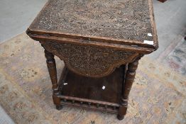 A late Victorian carved table having four drop leaves, turned legs and spindle gallery to lower
