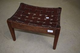 An early 20th Century Arts and Crafts foot stool having leather lattice strap top, in the style of
