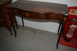 A reproduction Regency mahogany serpentine fronted console table having triple frieze drawers, on
