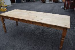 A natural pine kitchen dining table on turned legs with triple frieze drawer, approx. 227 x 90cm
