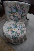A vintage low seat nursing chair having original upholstery and later loose cover